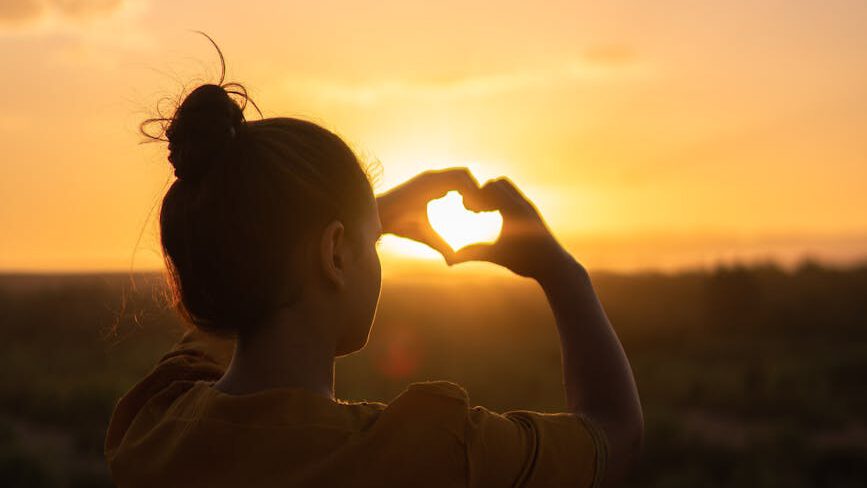 woman sitting while showing heart sign hands